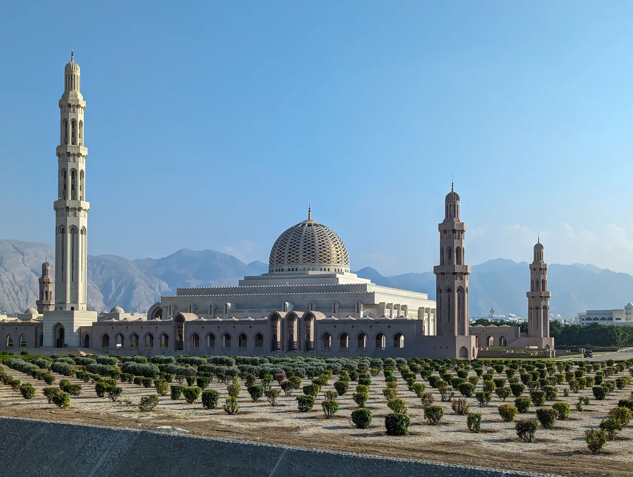 Sultan Qaboos Grand Mosque in Muscat with its gold dome and minarets against the Al Hajar Mountains